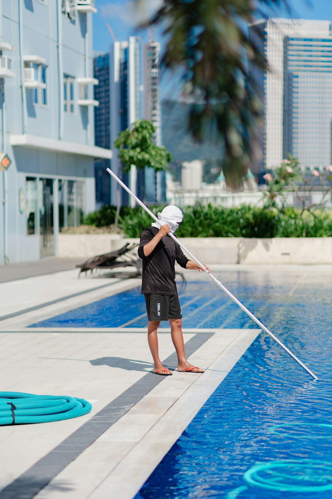 man-cleaning-a-swimming-pool-with-a-long-pole-z183eqfxutw